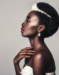 Beautiful black skin young woman with red lips in white gown and pearl tiara. Beauty shot on grey background. Copy space.